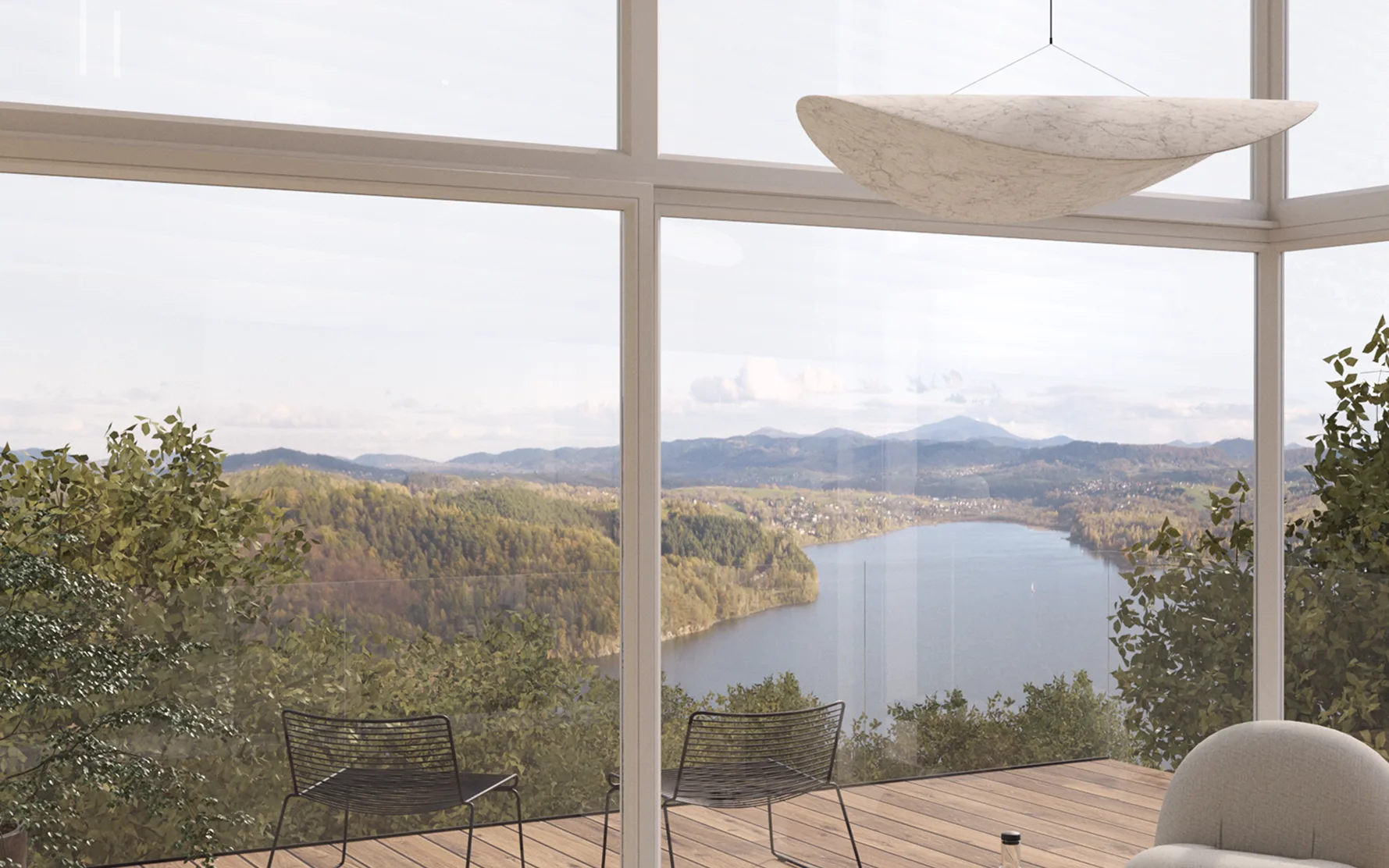 Panoramiczny widok z willi Treesna na Jezioro Żywieckie i góry, widoczny przez duże przeszklone okno, z tarasem i nowoczesnymi krzesłami w pierwszym planie.