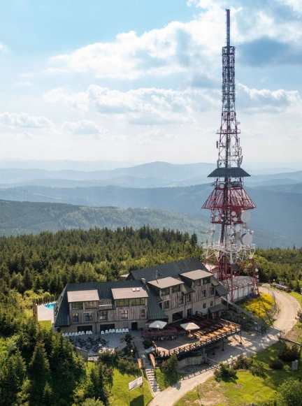 Turyści na drewnianej platformie widokowej na Skrzycznem, podziwiający rozległy krajobraz górski Beskidu Śląskiego.