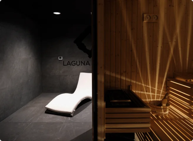 Eleganckie wnętrze spa z nowoczesną sauną z podświetlanym drewnem i białą leżanką w ciemnoszarym pomieszczeniu z napisem „Laguna” na ścianie.